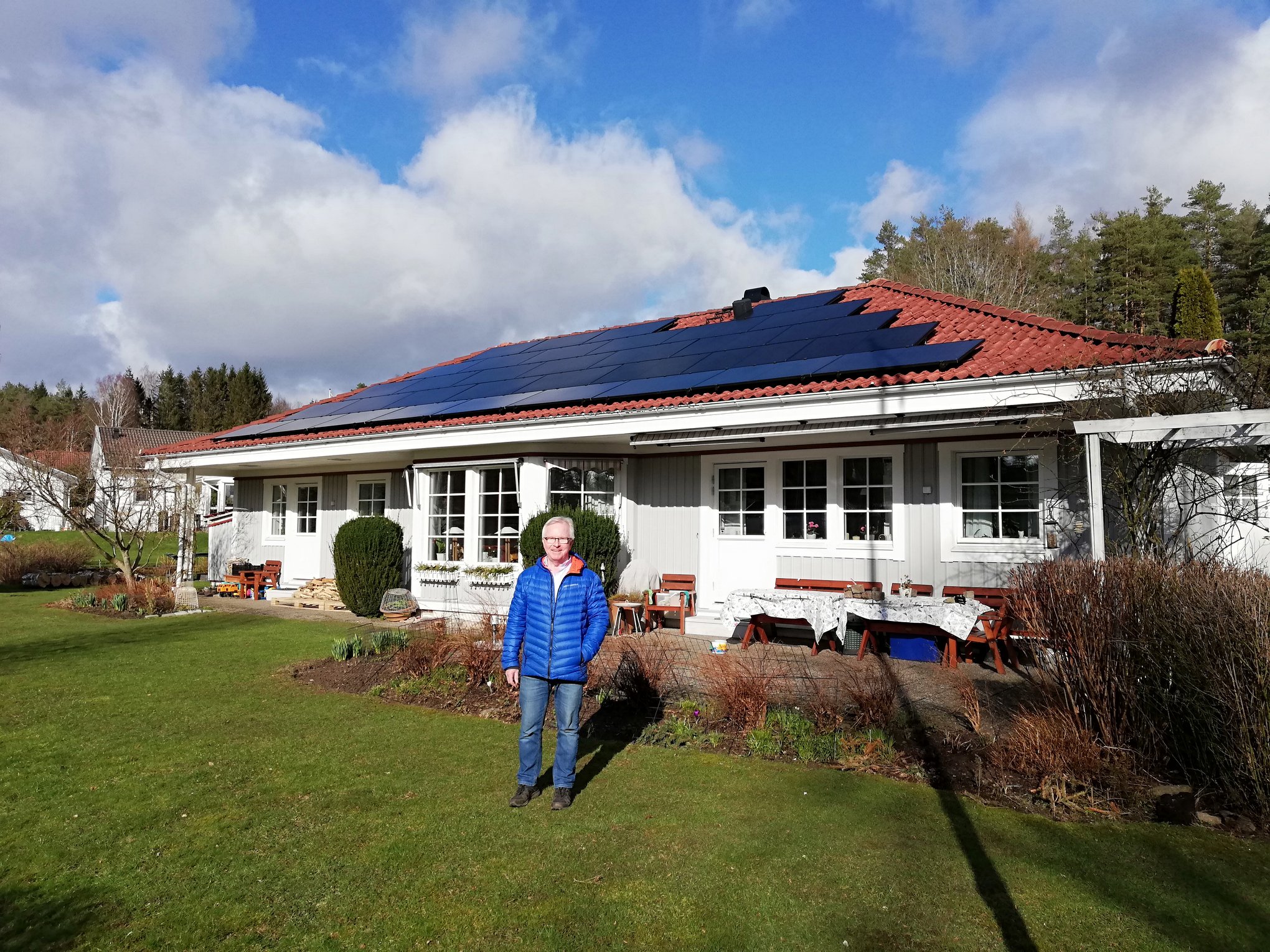 Villa med solpaneler i Sala och nöjd kund framför huset