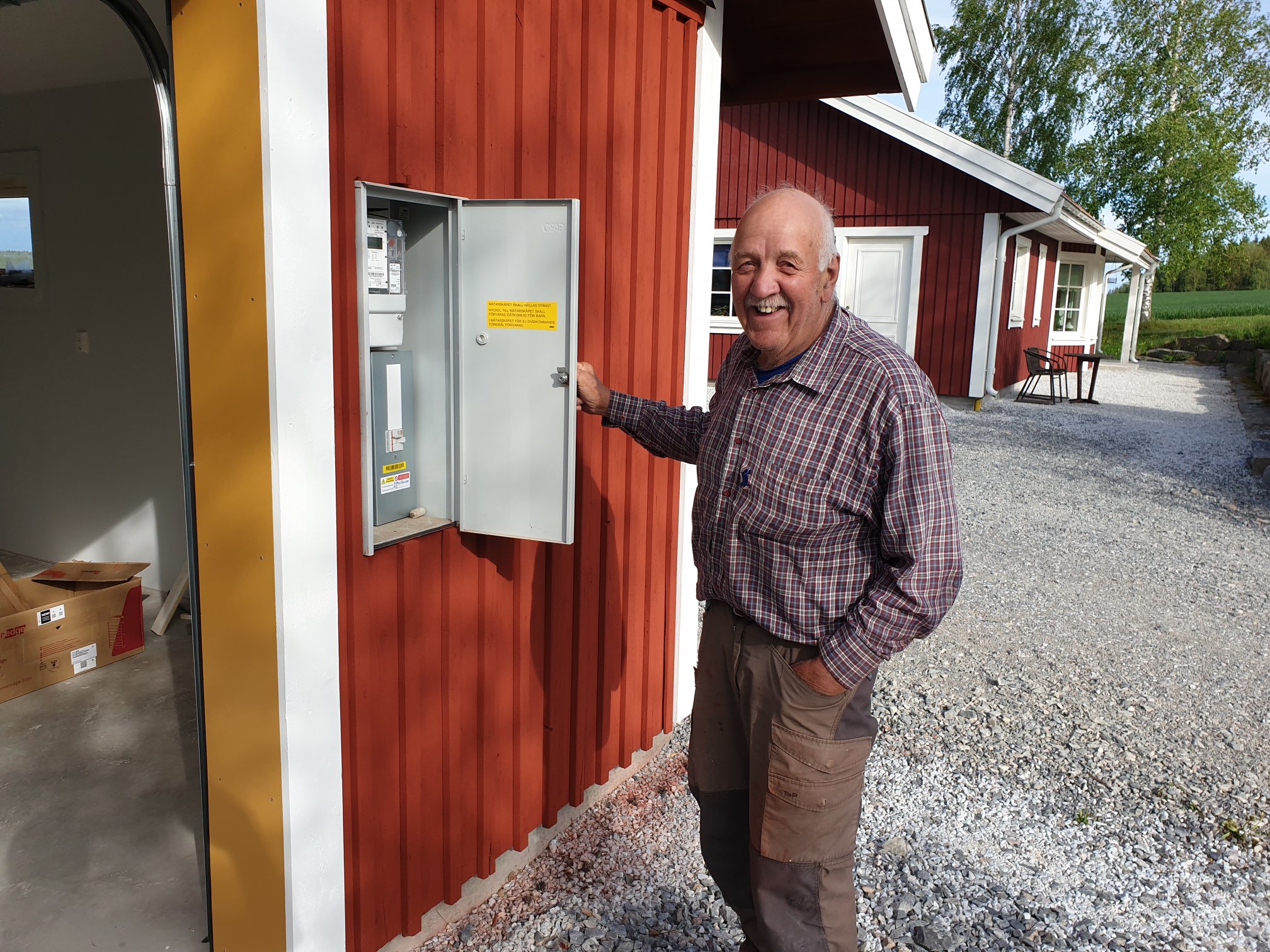 en nöjd kund vid elcentral i röd byggnad installerad för solceller Sala